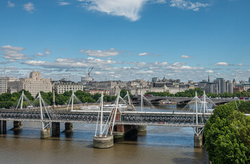 London, UK - July 4, 2022: Wide cityscape with Hungerford and Waterloo bridges over brown water...