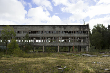 ruined industrial building on stilts with a broken wall of glass fragments. A picture of desolation and destruction. Nature destroys human structures