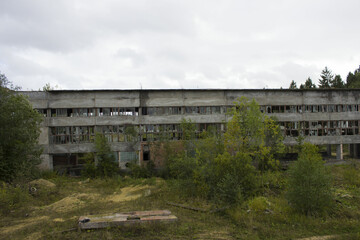 ruined industrial building on stilts with a broken wall of glass fragments. A picture of desolation and destruction. Nature destroys human structures