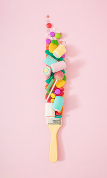 Creative junk food concept of paint brush that leaves tasty candy instead of paint. Pastel pink background.