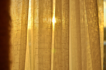 The golden sunset sun shines through the curtains