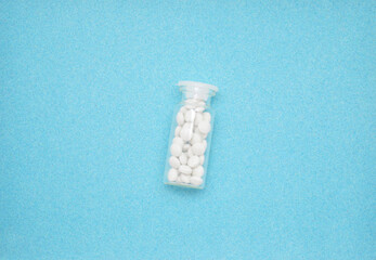 white small pills in a glass jar on a blue background