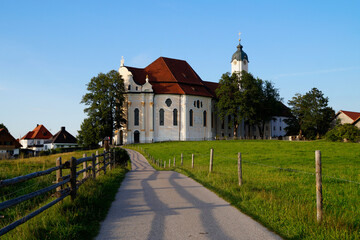 Fototapeta na wymiar The Pilgrimage Church of Wies (German: Wieskirche) is an oval rococo church in the Bavarian Alps on a sunny day in August (Steingaden, Weilheim-Schongau district, Bavaria, Germany)