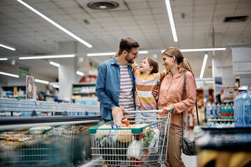 Happy embraced family enjoys in shopping at supermarket.