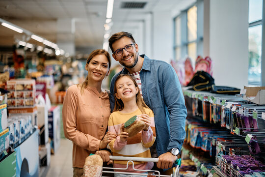 Portrait of happy family shopping in supermarket and looking at camera.