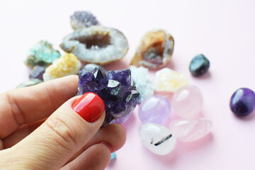 Beautiful dark purple amethyst crystals in hand. Druse of amethyst in a woman's hand against the background of other precious stones.