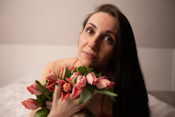 portrait of a young beautiful girl with dark hair, who pressed flowers to her face
