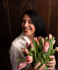 a brunette woman holds tulips and rejoices
