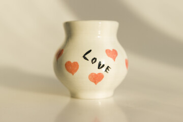 small white pot with hearts and the inscription Love. ceramic product. author's work