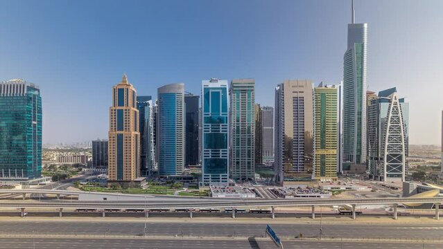 Aerial panoramic view of Jumeirah lakes towers skyscrapers during all day timelapse with traffic on sheikh zayed road and metro line. Shadows moves very fast and reflections on a glass