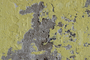 Vintage wall texture. Weathered rough surface of a concrete wall with peeling plaster and faded yellow paint. Great for background and design. Closeup. High resolution.