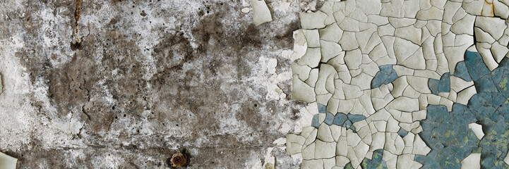 Peeling paint on the wall. Panorama of a concrete wall with old cracked flaking paint. Weathered rough painted surface with patterns of cracks and peeling. Wide panoramic grunge texture for background