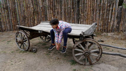 The child is sitting in a wooden cart. The girl leaned down. Countryside. Tired look. Cold weather....