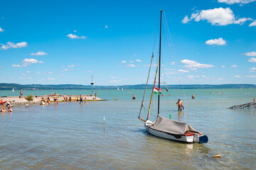 Picturesque view of the beach at the southern shore of Lake Balaton with sailing boat in the foreground.