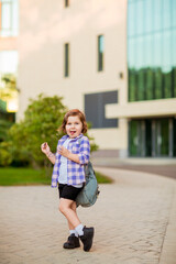 Naklejka premium a little schoolgirl, standing in glasses,near the school building,with a backpack