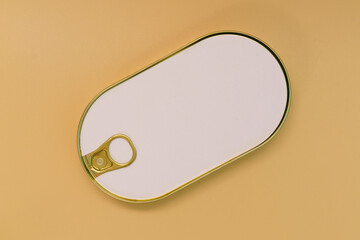 Closed golden rounded empty sardine fish tin can with an empty white paper mock up on a yellow...