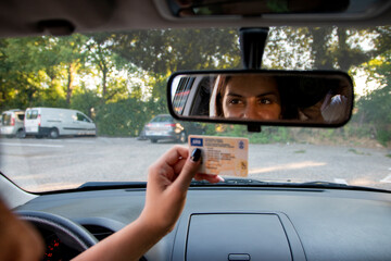 Teenager girl  showing his driver's license in the car window after passing the exam