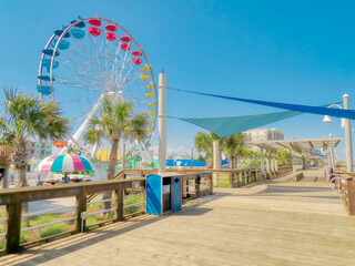 A beach view of a Ferris wheel by a wooden boardwalk at Carolina Beach, North Carolina in pastel colors. - obrazy, fototapety, plakaty