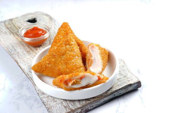 Triangle Fried Risoles or Risol mayo  is a typical Indonesian traditional street food . served with chili sauce on white background