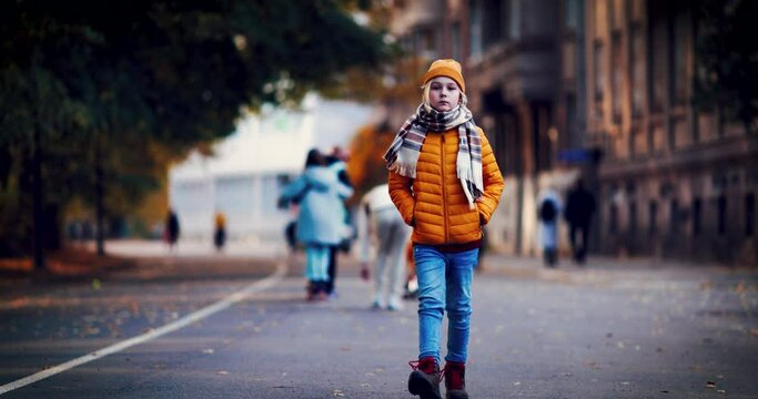 young boy walks on crowded autumn street