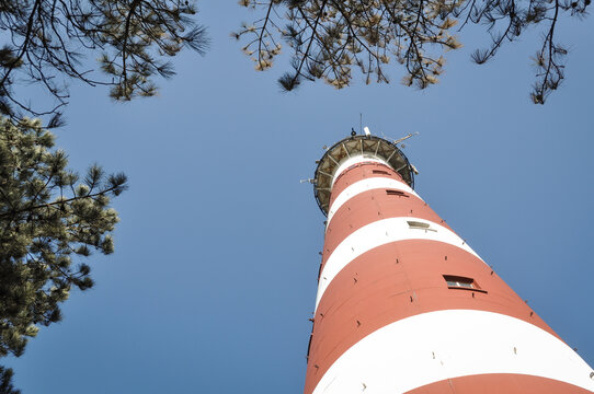 lighthouse of Ameland, Netherlands,  in red and white stripes in seen from below with blue sky
