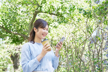 屋外で笑顔でスマホを使う女性