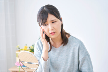 自宅で顔のシミに悩む女性