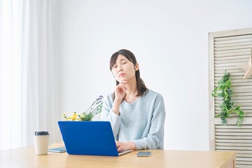 自宅でノートパソコンの前で考える女性