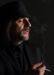 Portrait of middle aged man wearing black clothes and black hat posing in the studio