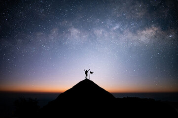 Silhouette of businessman standing on top of the mountain over night sky with star, Milky Way and...