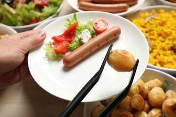 Woman taking food from buffet table, closeup