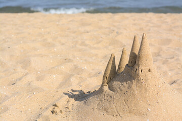 Beach with sand castle near sea on sunny day. Space for text