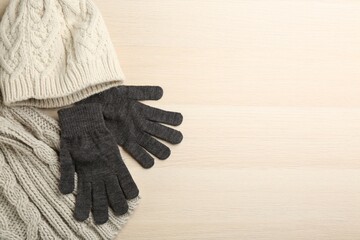 Stylish gloves, scarf and hat on white wooden background, flat lay. Space for text