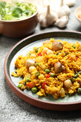 Delicious rice pilaf with vegetables on grey table
