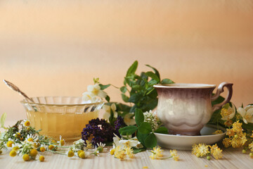 Cup of hot aromatic tea, honey and different fresh herbs on white wooden table
