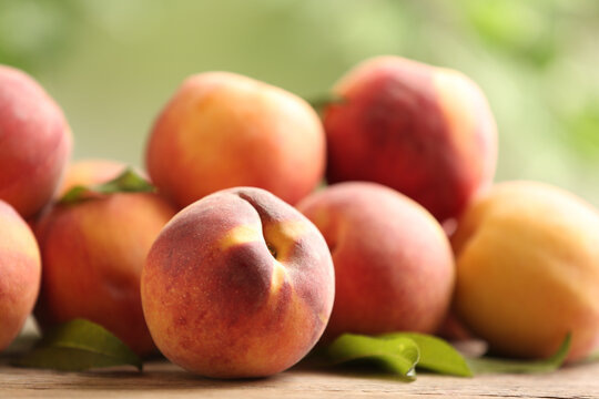 Fresh sweet peaches on wooden table outdoors, closeup
