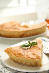 Piece of delicious pie with meat and basil on white table