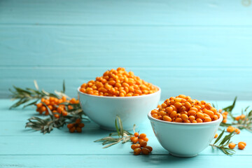 Fresh ripe sea buckthorn on light blue wooden table. Space for text