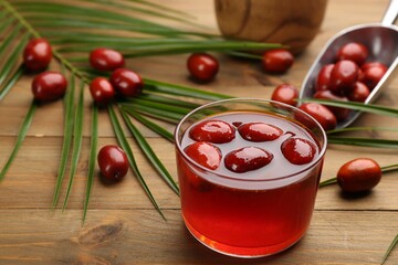 Palm oil in glass bowl with fruits and tropical leaf on wooden table