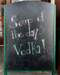 vFunny chalkboard sign in front of a bar that reads Soup of the Day; Vodka!