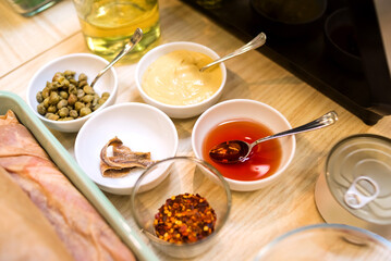 bowls of sauce ingredients: capers, anchovies, mustard, sunflower oil, chili pepper flakes, grape vinegar