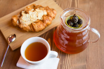 Breakfast in the cafe. juniper tea with lime served in a glass chemex, a cup of hot tea and a croissant with almonds.