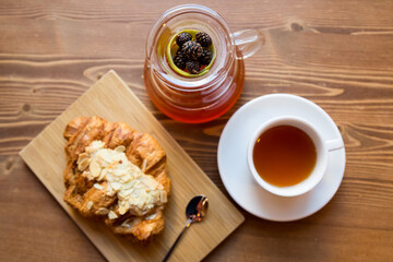 Breakfast in the cafe. juniper tea with lime served in a glass chemex, a cup of hot tea and a croissant with almonds.