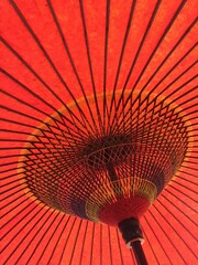 Under a large red paper Japanese umbrella
