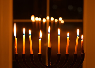 Nine Chanukah candles in front of window at night