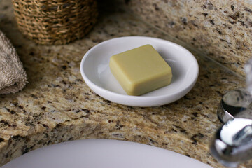 a bar of zero waste soap on white dish at bathroom sink