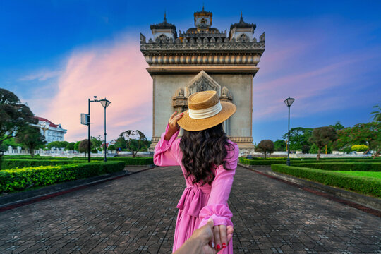 Women tourists holding man's hand and leading him to Patuxai in Vientiane, Laos.