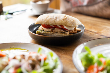 Pesto sandwich with chicken tomatos and mozzarella on the table in summer restaurant, natural light