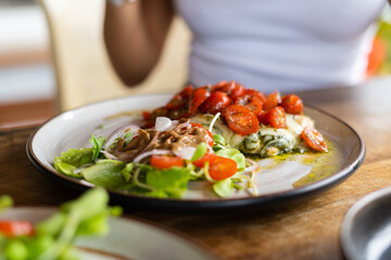 Woman having chicken pesto with cheese and tomatoes in summer cafe