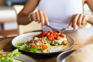 Woman having chicken pesto with cheese and tomatoes in summer cafe